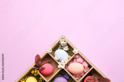 Divided box with beautiful Easter eggs on color background