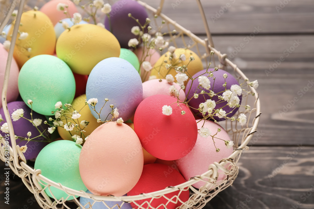 Obraz premium Basket with beautiful Easter eggs on wooden background