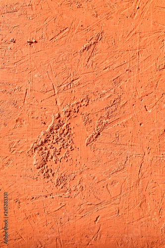 Blurred abstract background. The texture of a painted concrete rough surface with cracks and irregularities in orange. Cropped shot, vertical, place for text, nobody. The concept of repair and design.