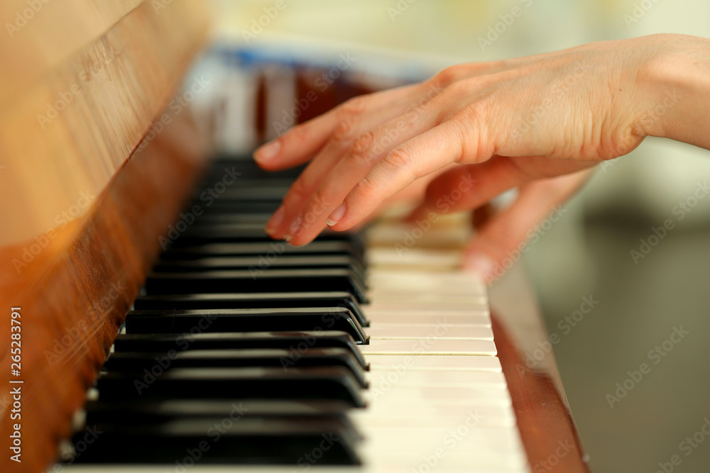 Female hands of a pianist playing the piano. Background, blur, close-up, cropped shot, side view. Concept of art and hobby.