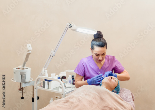 Female young beautician making facial lifting injections photo