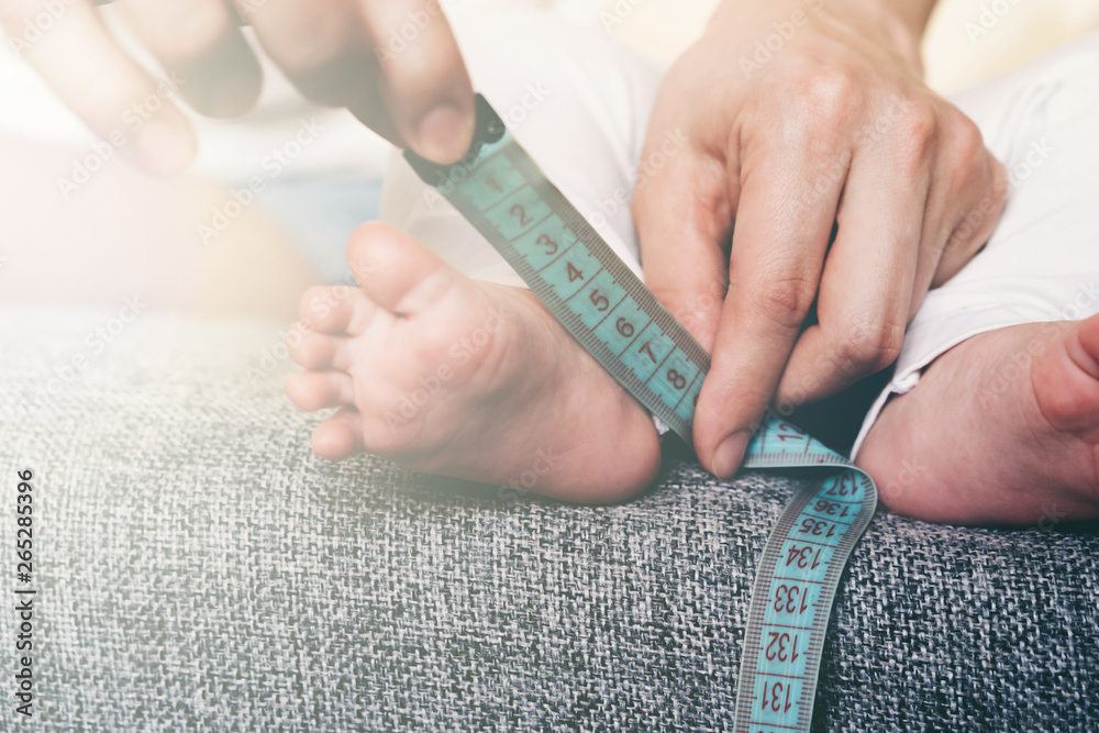 Close-up of a newborn's foot measured by a measuring tape, a conceptual illustration of development and growth in any business.