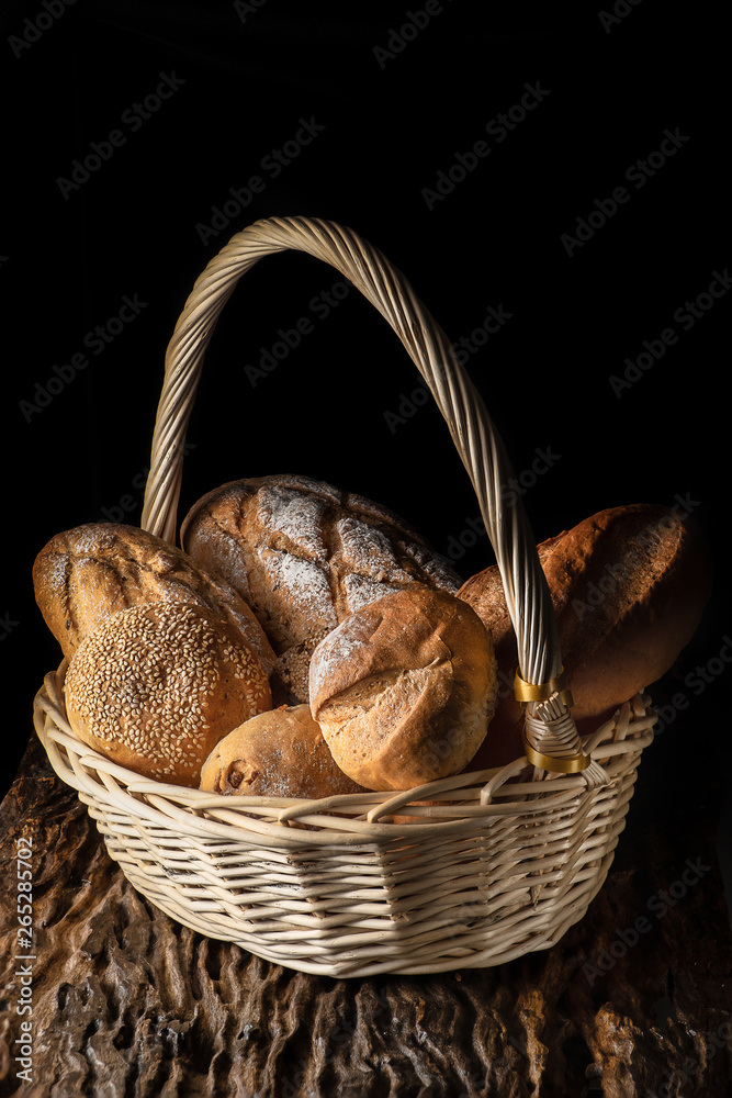 food background of a basket with assortment of bread on wooden plank with dark background