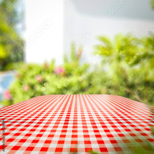 Tablecloth of red and white color and summer background of garden. Free space for your decoration. 