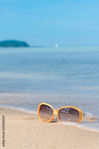 Fashion sunglasses on the beach, blurry blue sea and sky background