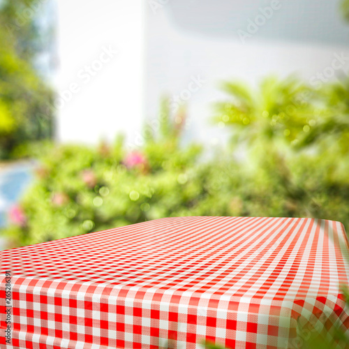 Tablecloth of red and white color and summer background of garden. Free space for your decoration. 