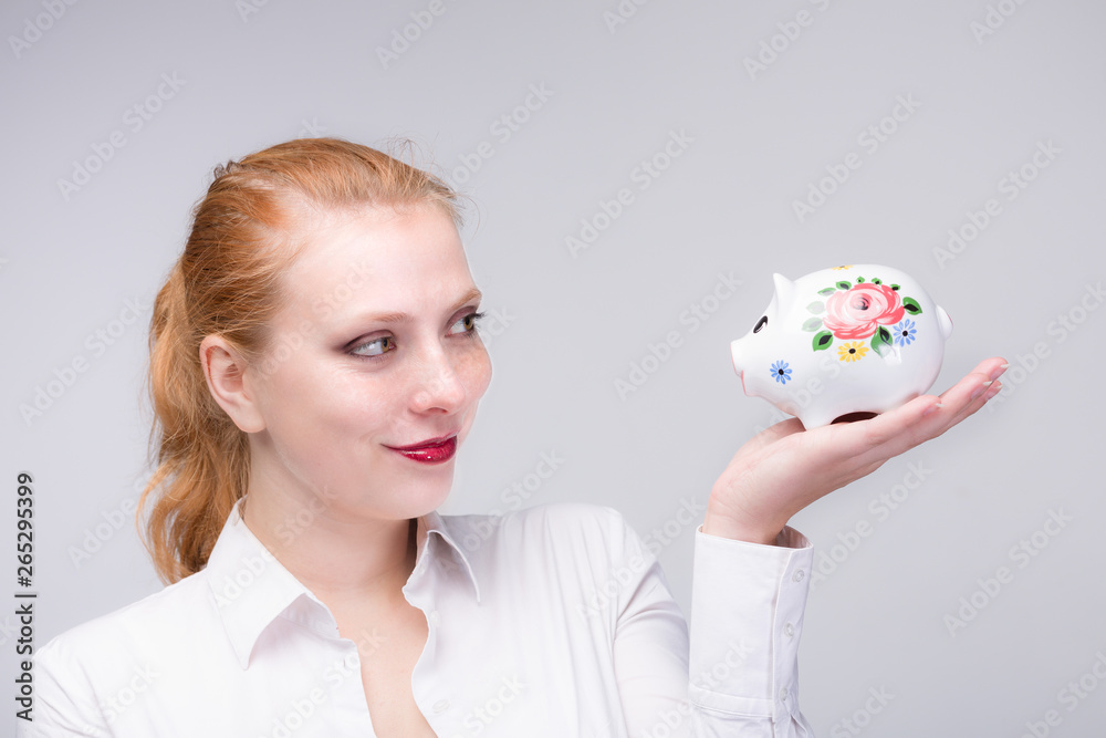 young red haired woman with her piggy bank young red haired woman with her piggy bank