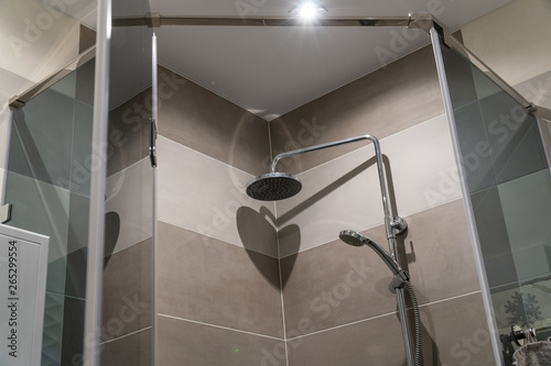 Gray glass shower cabin. The door is closed. Beautiful shower with traces of droplets and lime in bathroom of porcelain stoneware. Gray shades