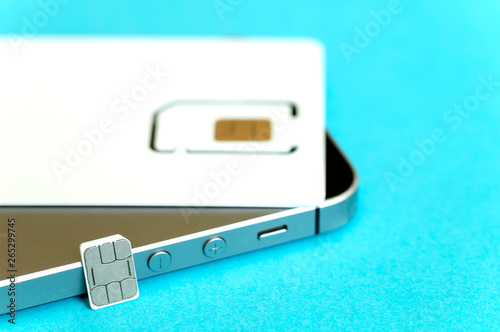 SIM card in a package blurred and micro SIM card, mobile phone on a blue background, close-up, top view © Антон Скрипачев