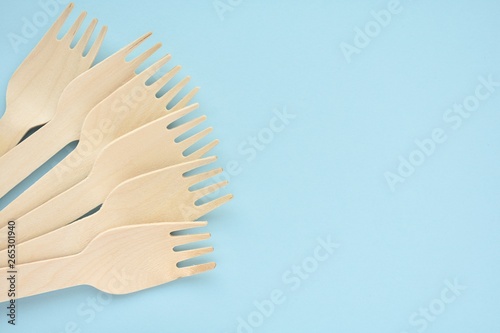 Wooden disposable forks on blue background  natural eco friendly  zero waste product  top view with copy space.