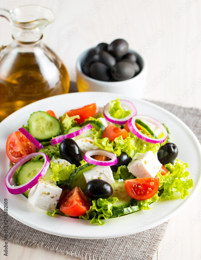 Fresh Greek salad made of cherry tomato, ruccola, arugula, feta, olives, cucumbers, onion and spices. Caesar salad in a white bowl on wooden background. Healthy organic diet food concept. Fresh Greek salad made of cherry tomato, ruccola, arugula, feta, olives, cucumbers, onion and spices. Caesar salad in a white bowl on wooden background. Healthy organic diet food concept.