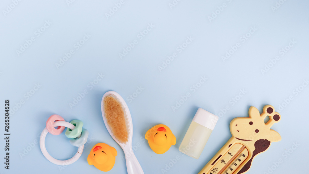 Obraz premium Baby bath products on blue background with copy space. flat lay soap bar, yellow rubber duck and liquid soap, toy