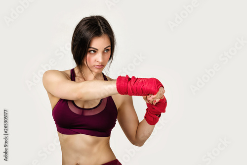 beautiful woman boxer with red boxing tape on wrist. Fitness girl preparing for boxing training