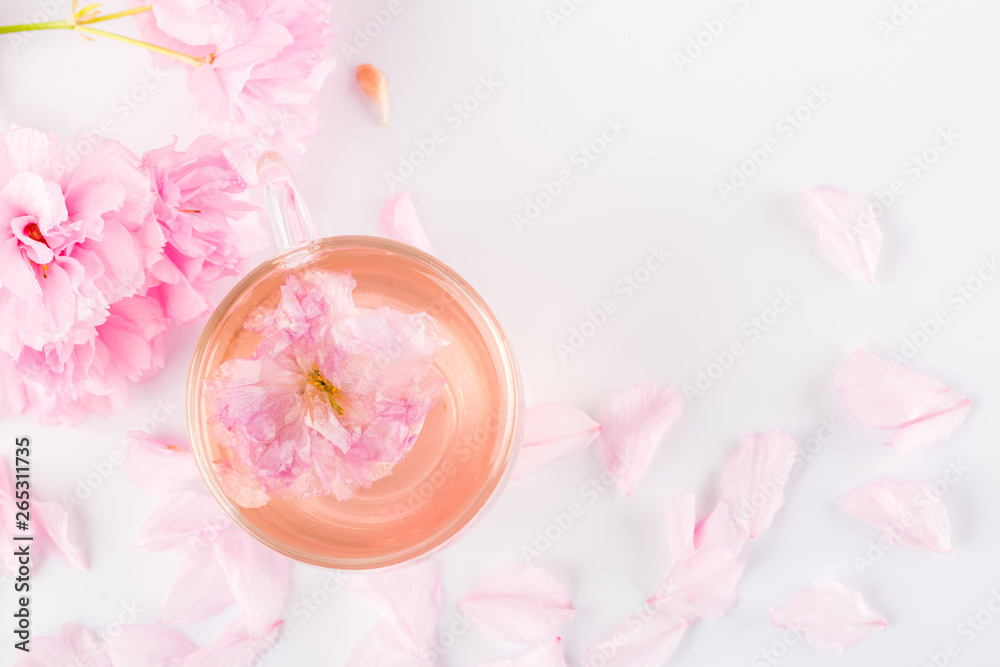 Cup of pink cherry blossom herb tea on white, Top view