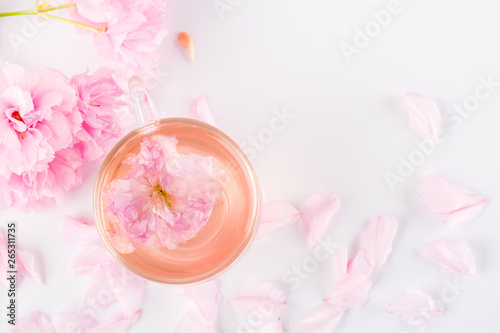 Cup of pink cherry blossom herb tea on white, Top view