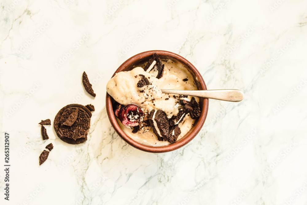 Banana vegan ice cream with cherries and oreo cookies on a white marble background.Top view. Banana vegan ice cream with cherries and oreo cookies on a white marble background.Top view.