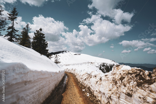 Narrow mountain dirt road has two sides off snow in winter 