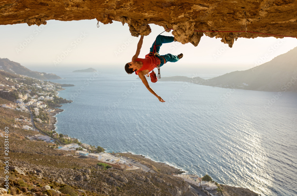 Male rock climber on challenging route going along ceiling in cave - obrazy, fototapety, plakaty 