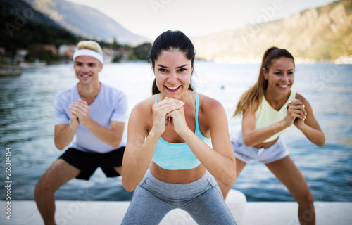 Group of happy friends or sportsmen exercising and stretching outdoor