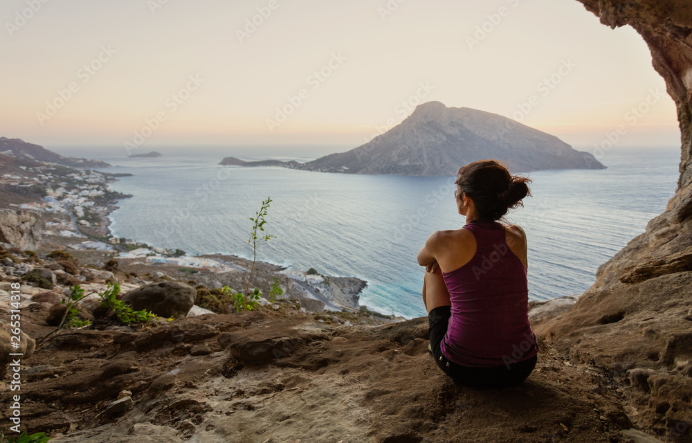 Female climber sitting in cave and watching sunset