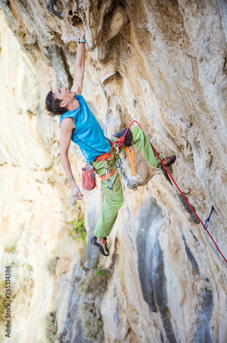 Young man climbing challenging route on overhanging cliff