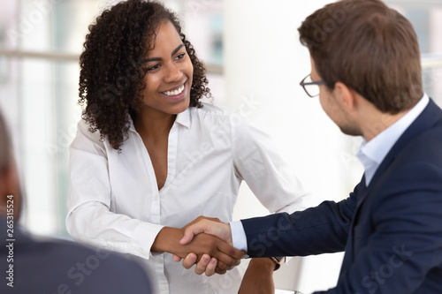 Smiling diverse businesswoman and businessman handshake make deal at meeting