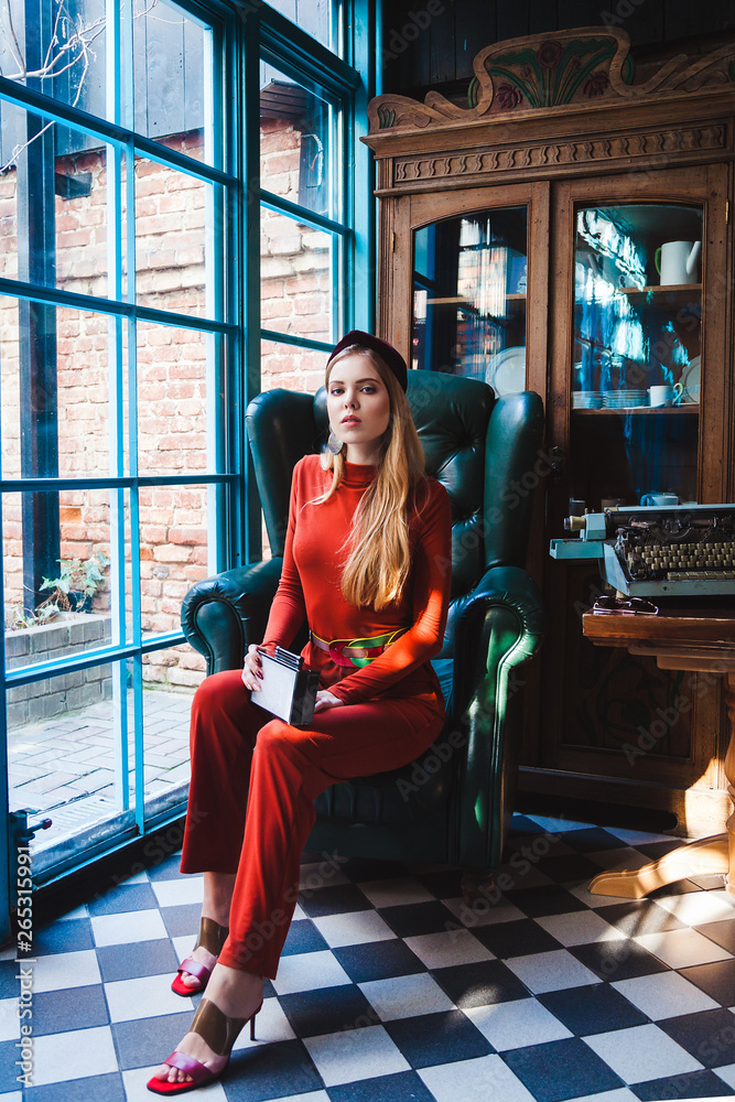 beautiful young model with long hair sits on a chair and looks into the camera beautiful young model with long hair sits on a chair and looks into the camera