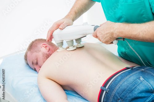 Doctor does transcranial magnetic stimulation, electrotherapeutic treatment of the back. A chiropractor treats patient's thoracic spine. Physiotherapy. Neurology, Osteopathy, chiropractic. photo