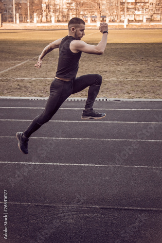 one caucasian male is doing a sprint start. running on the rubber track. Track and field runner in sport uniform. energetic physical activities. outdoor exercise, healthy lifestyle. running jumps