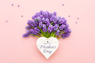 Spring lilac flowers and a heart shape card Happy Mother's Day on pink.