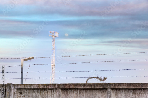 Concrete wall, against the backdrop of barbed wire, the concept of prison, salvation, refugee, lonely. Barbed wire fence detail.  Silhouette barbed wire and a watchtower