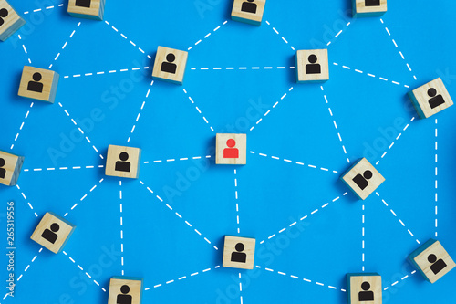 Leadership and network teamwork concepts Red businessman icon on the wooden block in the middle between the black business icon on the wooden blocks.