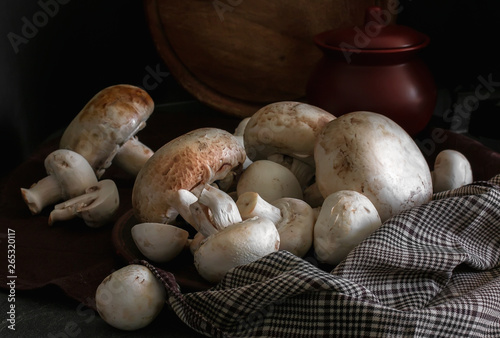 Fresh champignon mushrooms group on the table. Fresh vegetables mushrooms - the concept of healthy proper nutrition. Dark Food Photography