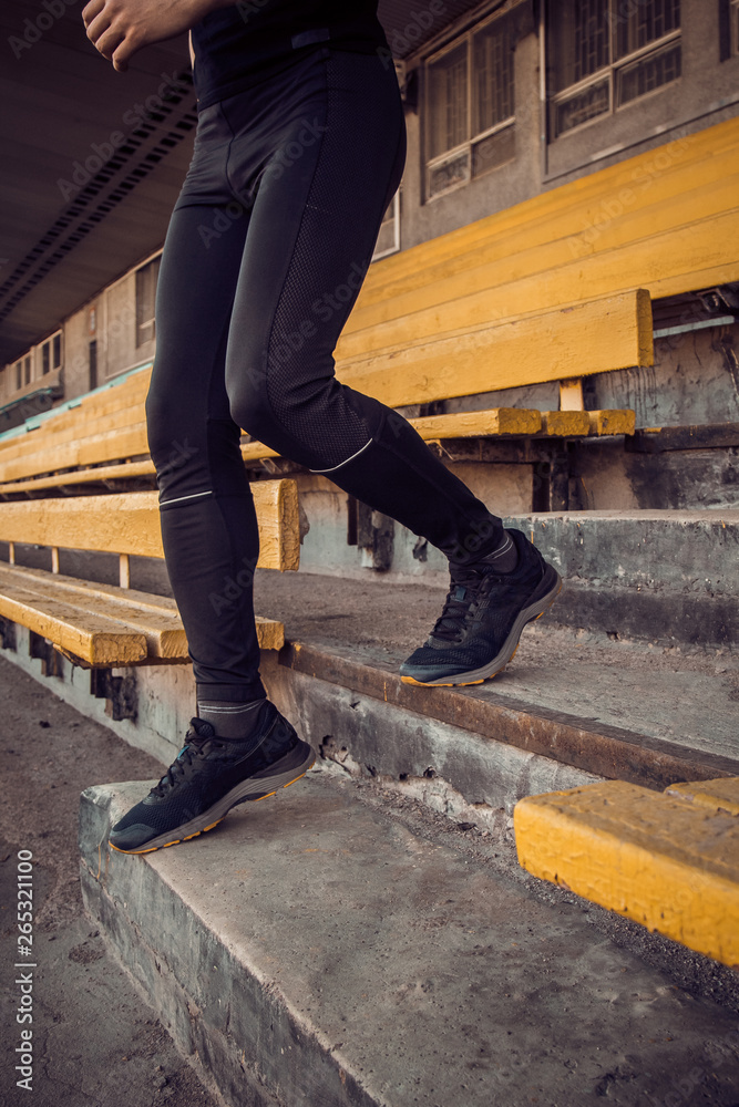 Caucasian man trains in running on the stairs. Track and field runner in sport uniform training outdoor. athlete, top view. step exercise. steps down. vertical Caucasian man trains in running on the stairs. Track and field runner in sport uniform training outdoor. athlete, top view. step exercise. steps down. vertical