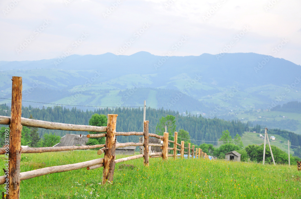 wooden fence in the field against the backdrop of mountains