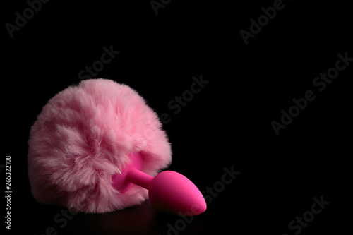 Pink anal tail plug isolated on black background.