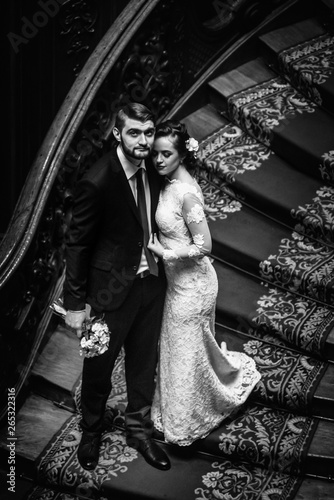 stylish luxury bride and handsome elegant groom on old wooden stairs on the background of luxury interior