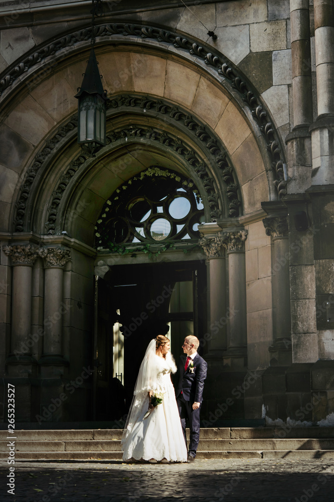 happy gorgeous bride and stylish handsome groom  on background of an amazing building church in the city