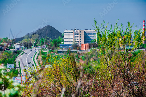 Green and bright, spring landscape. View of the city and the mountain from the field of flowering trees and young foliage. Juicy fresh grass and vegetation. Rostov region, Russia.