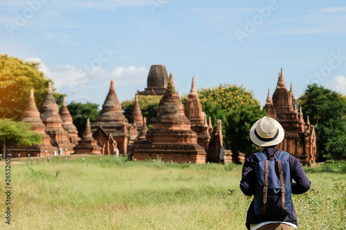 Young man traveling backpacker with hat, Asian traveler looking Beautiful ancient temples and pagoda, landmark and popular for tourist attractions in Bagan, Myanmar. Asia Travel concept © Jo Panuwat D