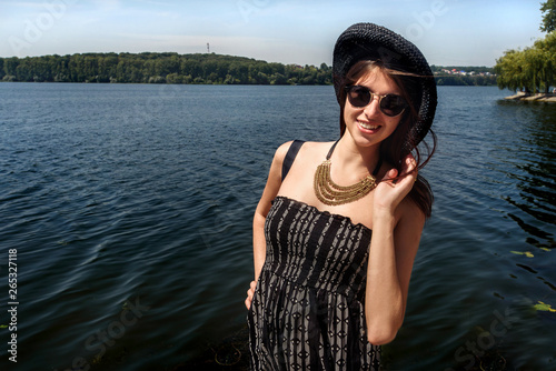 happy stylish woman hipster holding hat and smiling at sunny shore, summer travel concept, space for text © sonyachny