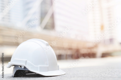 white hard safety wear helmet hat in the project at construction site building on concrete floor on city with sunlight. helmet for workman as engineer or worker. concept safety first. 