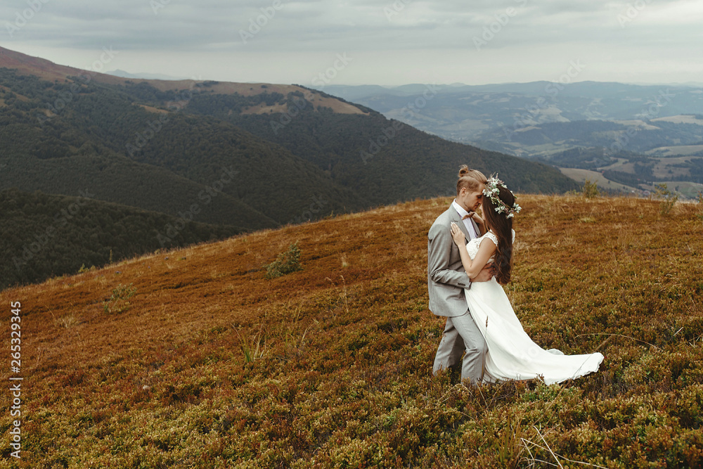 gorgeous bride and stylish groom hugging,  boho wedding couple, luxury ceremony at mountains with amazing view, space for text