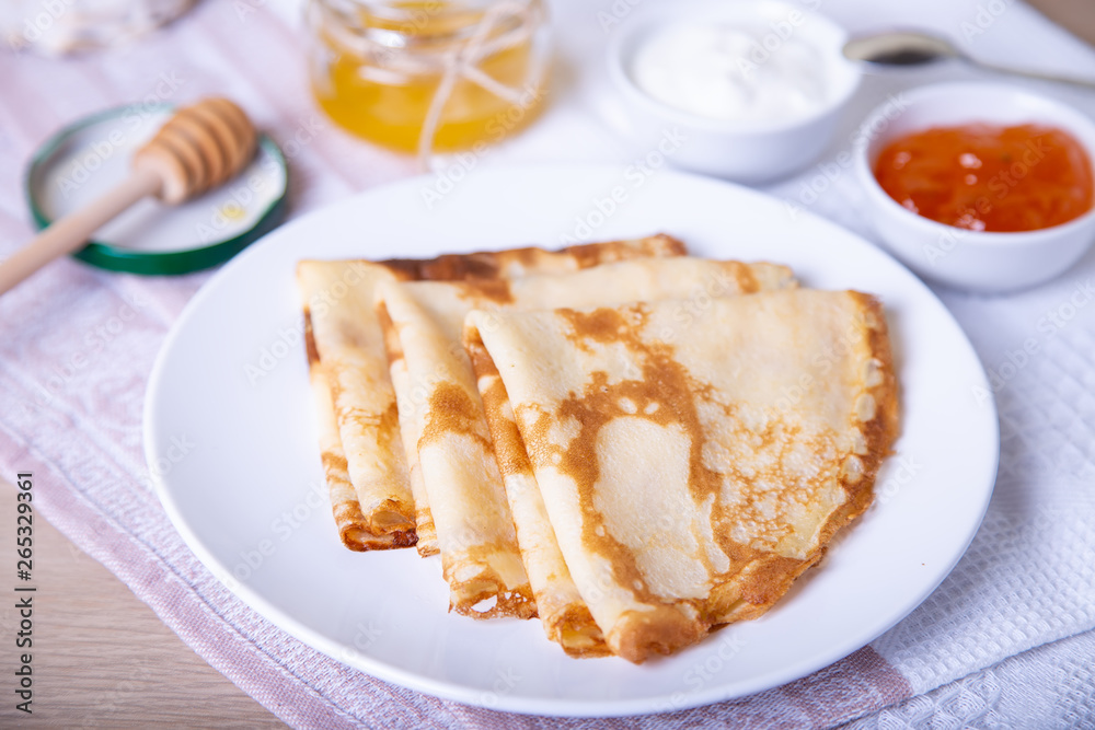 Traditional Russian pancakes with honey, sour cream and jam. Shrovetide. Maslenitsa week. Selective focus, close-up. Traditional Russian pancakes with honey, sour cream and jam. Shrovetide. Maslenitsa week. Selective focus, close-up.