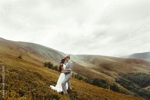 gorgeous bride and stylish groom hugging at sunny landscape   boho wedding couple  luxury ceremony at mountains with amazing view  space for text