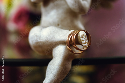 golden wedding rings on beautiful angel on the background of bride bouquet