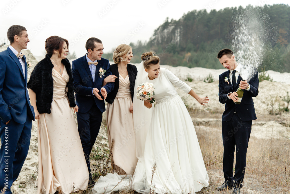 bride and groom with happy groomsmen and bridesmaids having fun and popping champagne, luxury wedding celebration, hilarious moment