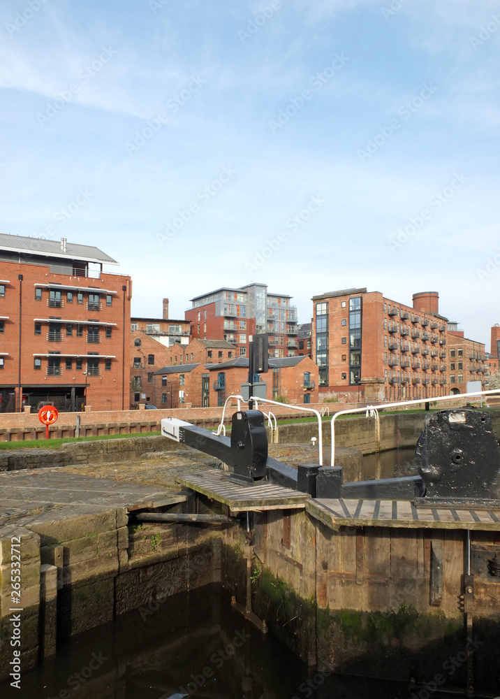 old wooden lock gates on the canal in leeds city center surrounded by waterside apartment buildings