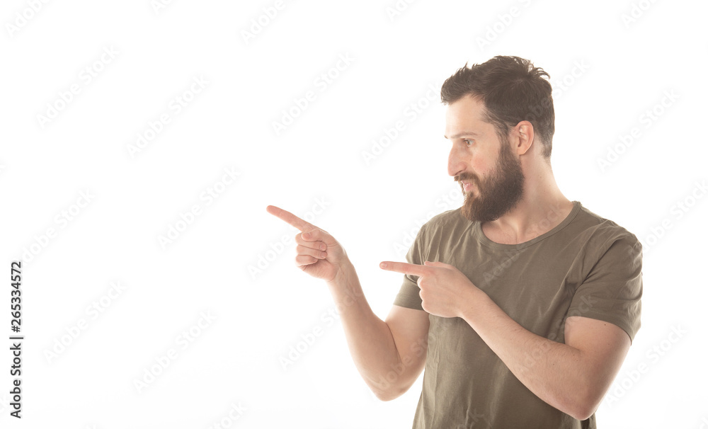 Young man in shirt pointing to the side with a finger to present a product or an idea while looking forward smiling on isolated white background Young man in shirt pointing to the side with a finger to present a product or an idea while looking forward smiling on isolated white background