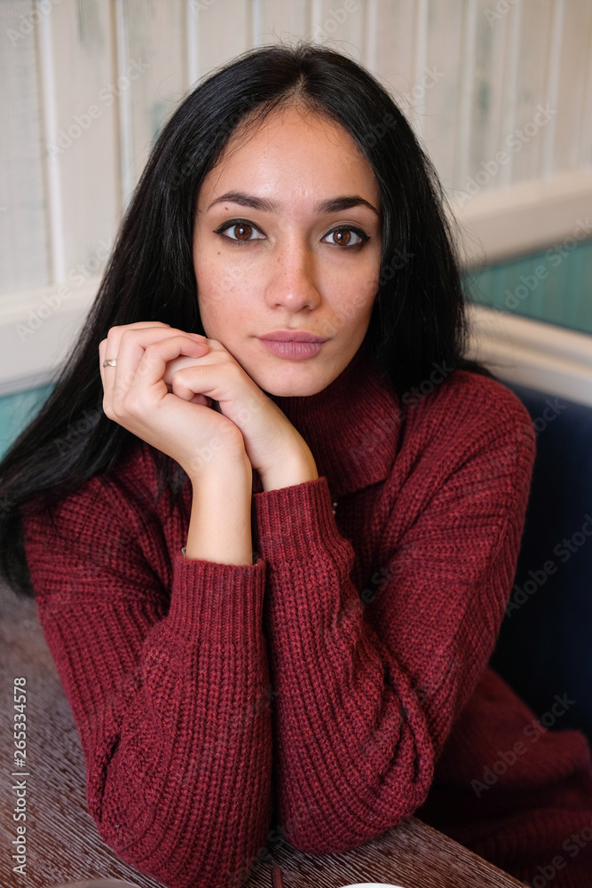 Closeup portrait of young attractive woman in red warm knitted sweater sitting in a cafe. Woman drinking hibiscus tea in the restaurant. Closeup portrait of young attractive woman in red warm knitted sweater sitting in a cafe. Woman drinking hibiscus tea in the restaurant.